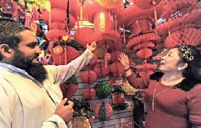 Afghan merchant Asal Abdullah talks to the owner of a lantern shop in Yiwu, Zhejiang province, on Sept 22. Yiwu is an internationally renowned hub of small commodity businesses and vibrant markets. Tan Jin / Xinhua