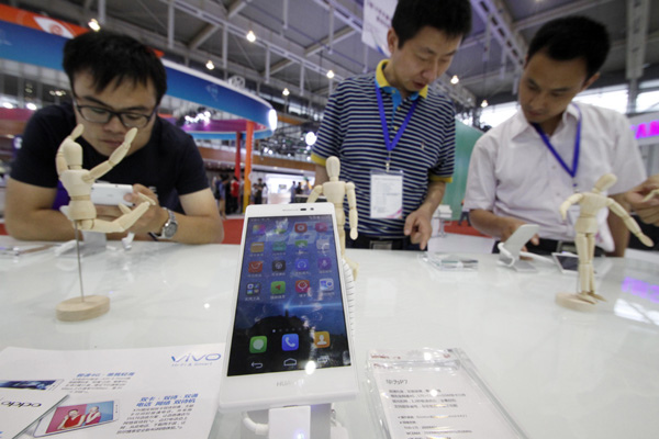 People look at the new handset during a mobile phone trade fair on June 27, 2014. [Provided to China Daily]  