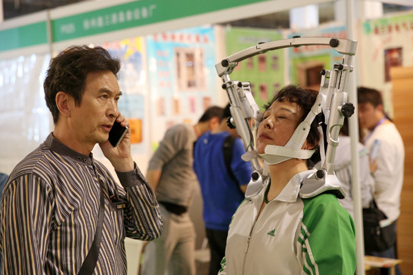 A visitor tries a device for the treatment of cervical vertebra problems at an international health industry expo in Beijing. The medtech market, including instruments and equipment, was valued at $22 billion in 2013. [Provided to China Daily]  