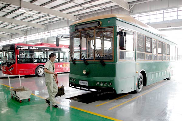 A worker helps get electric buses ready for delivery to Beijing, which now has Yinlong vehicles in operation for sight-seeing around the Forbidden City. [ZOU ZHONGPIN/CHINA DAILY]  