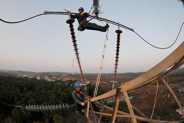 Workers check power transmission lines in Mingguang, Anhui province. Fixed-asset investment growth slowed to 15.9 percent year-on-year for the first 10 months. [Song Weixing / China Daily]  