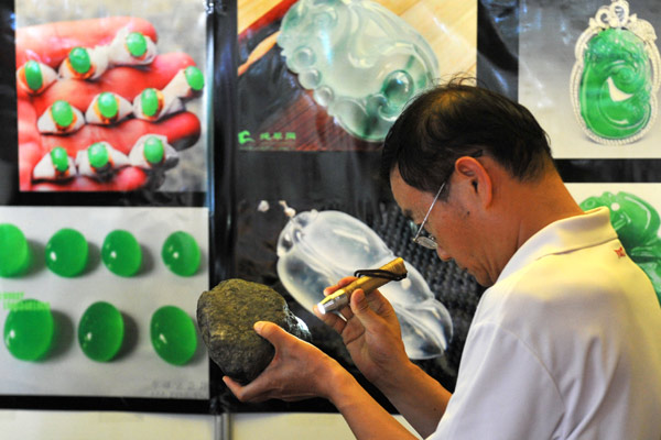A visitor scrutinizes a jadeite stone from Myanmar at the 2014 Pan-Asia Stone Exhibition in Kunming, Yunnan province, on July 10, 2014. The Bangladesh-China-India-Myanmar Economic Corridor is expected to spark a major expansion in infrastructure development, which will revitalize the economies involved. [Lin Yiguang / Xinhua]  