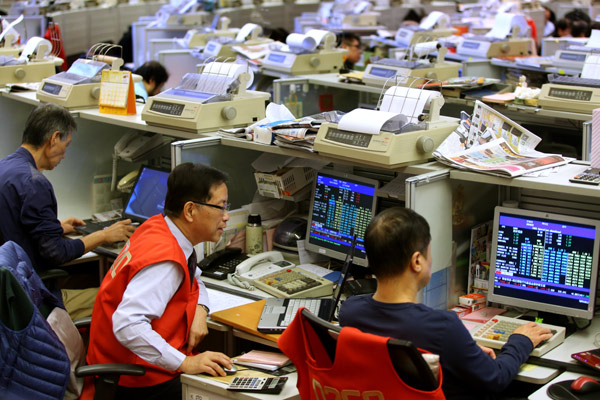 Traders monitor share prices during morning trading at the Hong Kong Stock Exchange on Monday. Stock Connect has opened channels for more capital flows between Hong Kong and Shanghai. [Roy Liu / China Daily]  