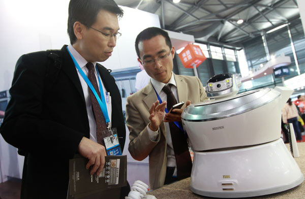 A salesman (right), shows a visitor how to operate an air purifier using his cellphone at an expo in Shanghai. [Pei Xin / Xinhua]  