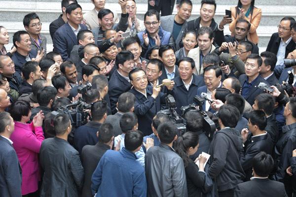 Premier Li Keqiang holds a traditional rattle given to him by a businessman at Yiwu International Trade City, Zhejiang province, on Thursday. He said the gift will be preserved at the National Museum of China as it represents the spirit of Yiwu. [Liu Zhen / China News Service]  