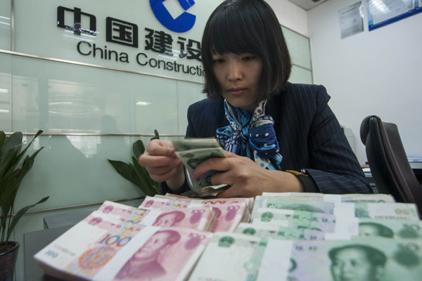 A clerk checks banknotes at an outlet of China Construction Bank Corp in Hai'an, Jiangsu province. The asymmetric interest rate cut could put pressure on lenders' profitability. [Xu Jiabao / China Daily]  