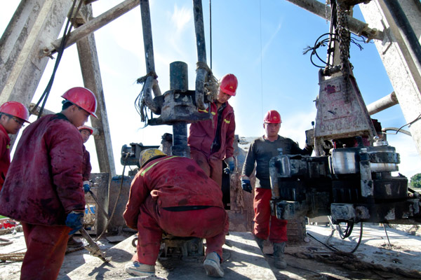 PetroChina workers set up a drill near Changchun, capital of Jilin province. The top oil and gas producer plans to sell 35 percent stakes in two of its major oilfields to private investors. [Photo / Xinhua]  