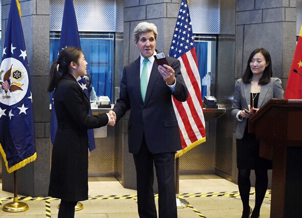 US Secretary of State John Kerry (centre R) prepares to give a visa to a Chinese woman at a press conference at the US Embassy in Beijing on November 12, 2014. WANG ZHAO/For China Daily  