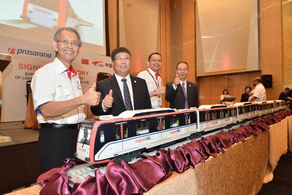 Zhou Qinghe (2nd from left), president of CSR Zhuzhou Electric Locomotive Co, looks at a model train in Kuala Lumpur, Malaysia, Oct 21, 2014. [Photo/Xinhua]  
