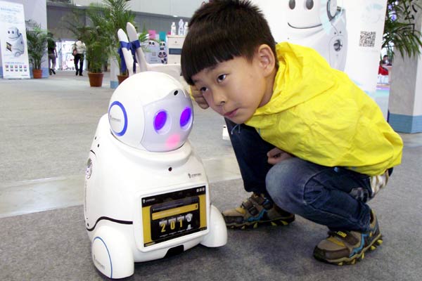 A boy listening to a household intelligent robot, that works on cloud-computing technology at the 10th China International Software Product & Information Service Trade Fair in Nanjing, Jiangsu province, in September. China's overall cloud-computing value chain is expected to be worth at least $122 billion by 2015. WANG QIMING/CHINA DAILY