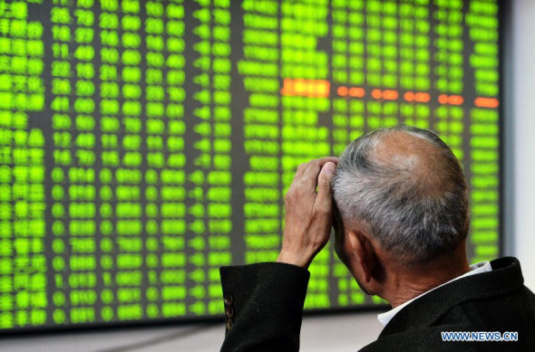 An investor looks through stock information at a trading hall of a securities firm in Hangzhou, capital of east China's Zhejiang province, Dec 9, 2014. (Xinhua/Long Wei) 