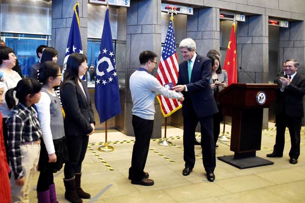 US Secretary of State John Kerry issues a visa to a Chinese man named Yang Bo at the US Embassy in Beijing on Nov 12. Insurance companies see larger demand for travel insurance from Chinese travelers after the US eased its visa policies. [Provided to China Daily]  
