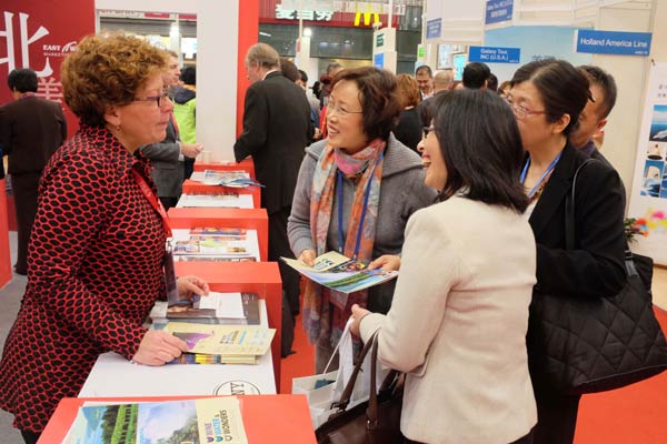 Prospective tourists check out information on travel to the United States at the US pavilion during the China International Travel Mart 2014 in November in Shanghai.[Provided to China Daily]   