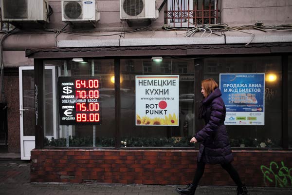 A woman walks past boards showing currency exchange rates in Moscow, Dec 16, 2014.[Photo/Xinhua]   