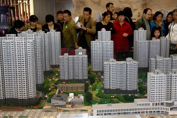 Potential home buyers check out models of upcoming property projects at a real estate company in Xuchang, Henan province. A report published by a unit of the Chinese Academy of Social Sciences' said realty prices will fall 5 percent in 2015.[Geng Guoqing / for China Daily]