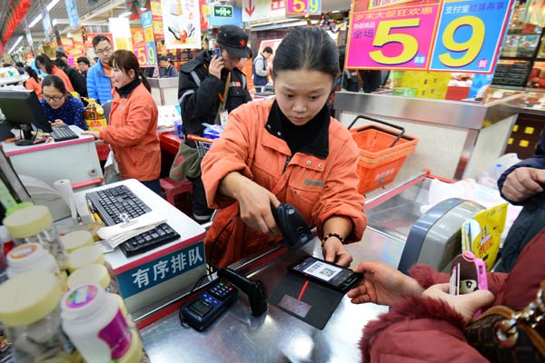 A salesperson scanning the quick response code from a customer's mobile phone at a retail outlet in Beijing. Alipay is launching a consumer financing service that allows shoppers to pay for online purchases the month after delivery. WANG JING/FOR CHINA DAILY