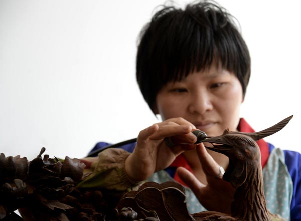 An artisan carves a phoenix on rosewood at a furniture factory in Dongyang, Zhejiang province. [Photo/China Daily]  