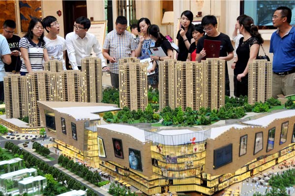 Potential homebuyers examine a property project model in Hangzhou, capital of Zhejiang province, Aug 31, 2014.[Photo/Xinhua] 