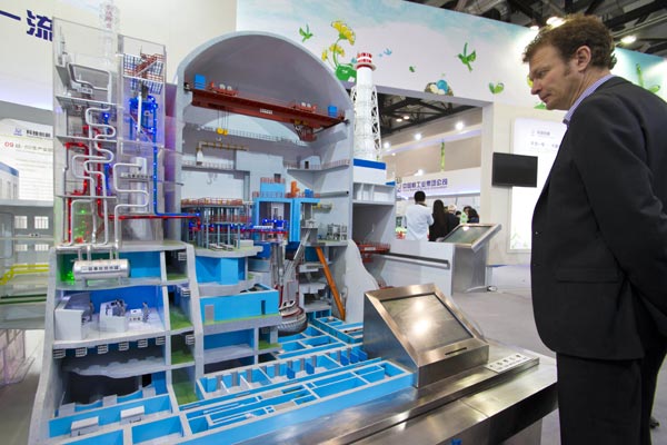 A foreign visitor examines a Chinese nuclear power plant model at an energy expo in Beijing. Foreign energy giants are pinning their hopes on China's nuclear market and its huge potential for growth. [Photo/China Daily]  