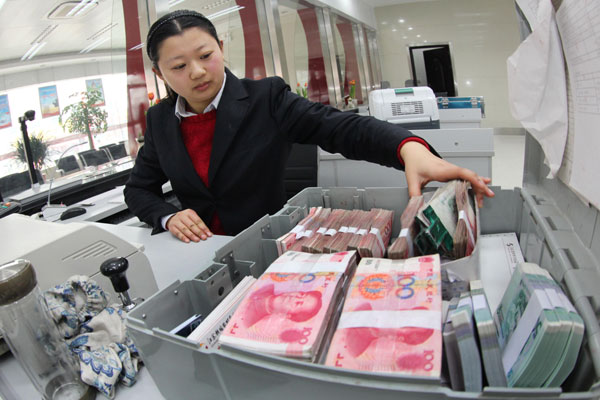 An employee prepares money at a commercial bank in Ganyu, Jiangsu province. New loans stood at 1.05 trillion yuan($169 billion)in March, up from an average of 981.8 billion yuan in January and February. SI WEI/CHINA DAILY  