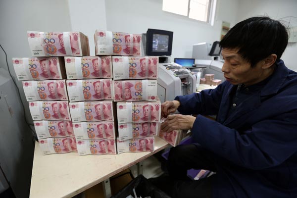 A clerk counts currency notes at an outlet of the Industrial and Commercial Bank of China Ltd in Wuxi, Jiangsu province. In December, the Chinese currency reached a record high share of 2.17 percent in global payments by value. [Photo/China Daily]