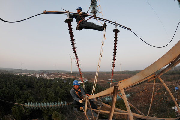 Workers check power transmission lines in Mingguang, Anhui province. [Photo provided to China Daily]