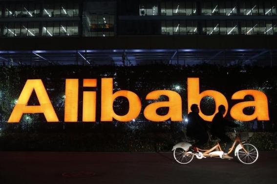 People ride a double bicycle past a logo of The Alibaba Group at the company's headquarters on the outskirts of Hangzhou, Zhejiang province Nov 10, 2014. [Photo: China Daily/Agencies]