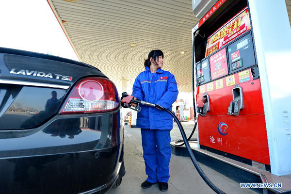 A worker fills up a car with fuel at a gas station in Cangzhou, north China's Hebei Province, Feb 9, 2015.[Photo/Xinhua]  