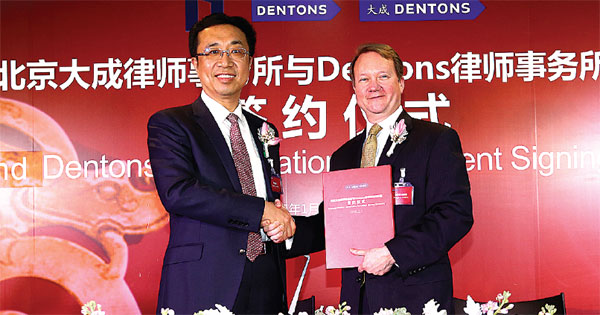 Peng Xuefeng (left), Dacheng's founding partner and chairman of the world's biggest law firm's global board, with Dentons Global Chairman Joe Andrew during the merger contract signing ceremony on Jan 27 in Beijing. [Photo provided to China Daily]  