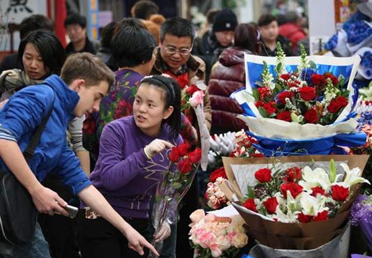 A foreigner asks about the price of roses at Laitai Flower Market in Beijing on Feb 13, 2014 ahead of Valentine's Day on Feb 14. [Photo by Wang Zhuangfei/ China Daily]