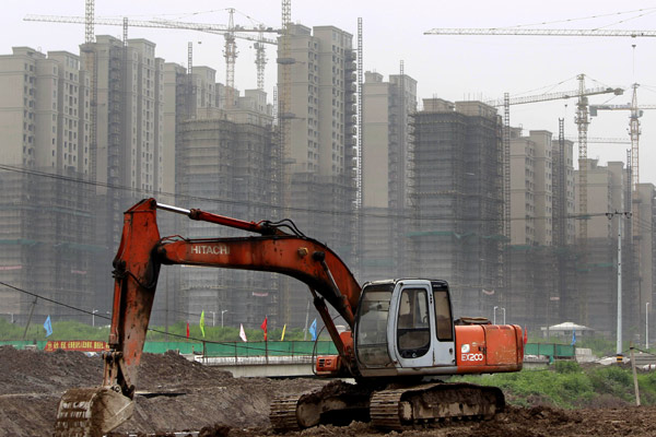 An excavator works near a residential building under construction in Baoshan district, Shanghai, in July. (Photo: Ding Ting/Xinhua)
