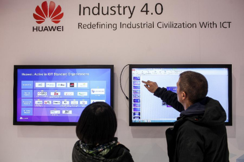 Two staff members work at Huawei's stand of the 2015 CeBIT Technology Trade fair in Hanover, Germany, on March 14, 2015. 