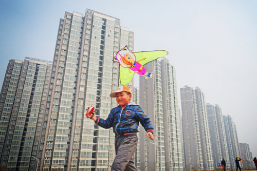 A boy flies a kite beside a massive residential project in Luoyang, Henan province, on March 8. Many local governments have ramped up efforts to bolster home sales after the moves to ease purchase restrictions barely worked. (Photo: Huang Zhengwei/For China Daily)