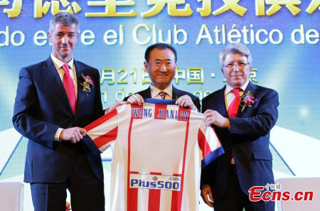 Wang Jianlin (M), chairman of the Dalian Wanda property group, together with Atletico Madrid CEO Gil Marin (L) and club president Enrique Cerezo (R), hold a jersey which features Wangs name on the back at a signing ceremony in Beijing on Jan 21, 2015. [Photo/Agencies] 