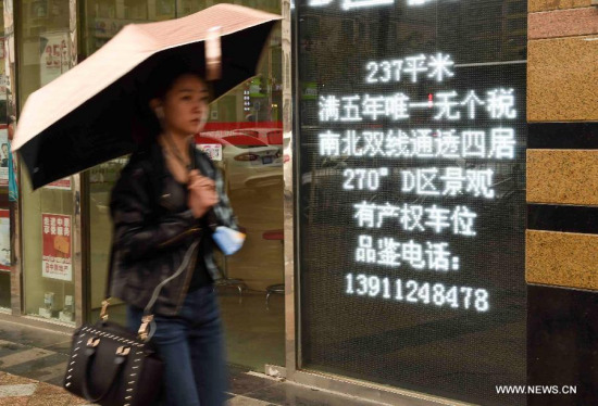 A pedestrian walks past a real estate agency in Beijing, capital of China, March 31, 2015. Chinese authorities on Monday decided to relax mortgage rules for second home buyers to address demand for improved housing and lift the sagging housing market. (Xinhua/Luo Xiaoguang) 