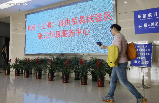 A citizen walks past a screen at the Zhangjiang Hi-tech District Management Committee in Shanghai, east China, April 20, 2015. China on Monday announced master plans for pilot free trade zones (FTZ) in Guangdong, Tianjin and Fujian and a plan for deepening reform and opening up in the Shanghai FTZ. (Xinhua/Fang Zhe)