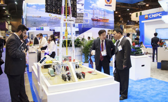   Liu Weijiang (second from right), former director of International Department and the OTC team leader at CNPC, talks to Li Chun Mao, general manager of CPNC's subsidiary CP International, Inc. in front of a drilling model. May Zhou / China Daily.  