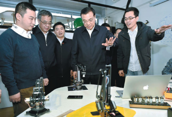 Premier Li Keqiang tried a remote control mechanical arm in Chaihuo Makerspace, an innovation platform in Shenzhen, Guangdong province on Jan 4, 2015. (Photo/China News Service)