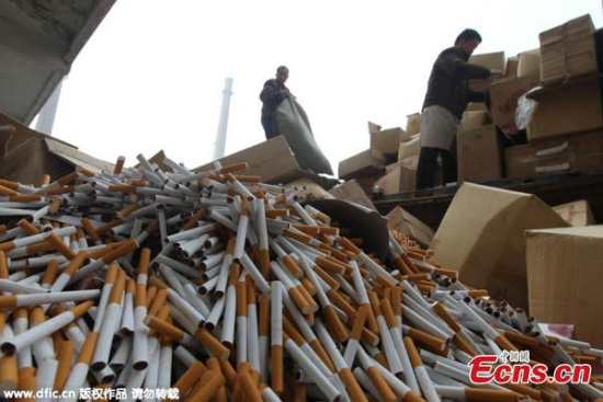 Workers dump counterfeit cigarettes at an incineration power plant in Xuchang, Central China's Henan province, March 13, 2015. (Photo/IC)
