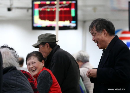Investors look through stock information at a trading hall of a securities firm in Shanghai, east China, March 18, 2015. (Photo: Xinhua/Pei Xin) 