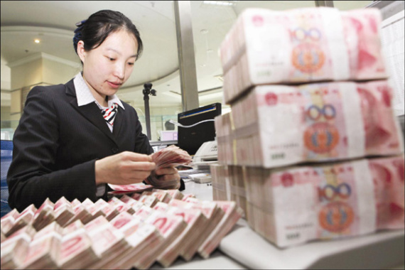 A teller counts money in a bank in Ganyu county, eastern Jiangsu province. The IMF is expected to declare soon that the currency is now fairly valued. (Photo/China Daily)