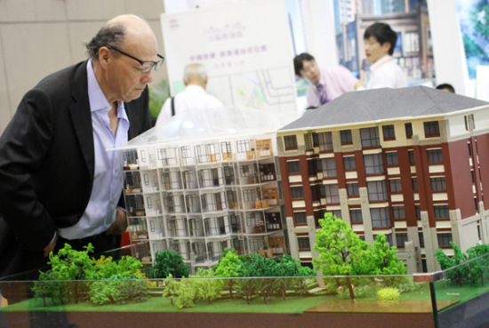 A potential foreign buyer studies a development model at an international housing exhibition in Beijing. (Photo/Chian Daily)