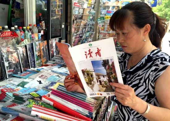   A reader checks the latest edition of Readers at a newspaper stand in Beijing on Wednesday. The popular magazine sells more than 200,000 copies of each edition. (Photo/China Daily)