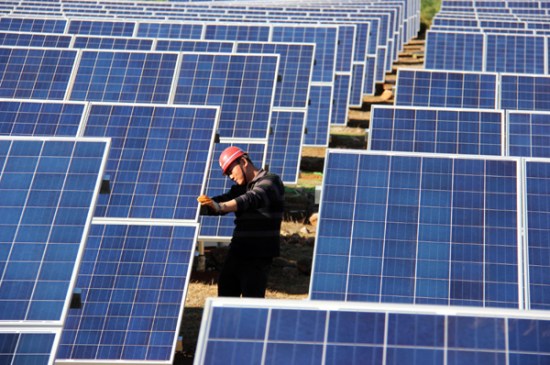 A worker installs solar panels at a solar photovoltaic power plant under construction in Weining, Guizhou province. (Photo/China Daily)