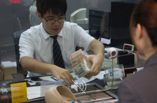 A teller undertaking a customer transaction at a branch of Industrial and Commercial Bank of China Ltd in the Shanghai free trade zone. Enterprises in the zone had settled cross-border capital flows of 160 billion yuan ($25.8 billion) through free trade accounts by June 1. (Gao Erqiang/China Daily)