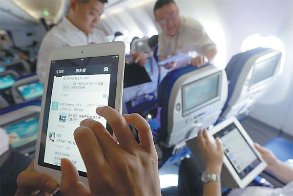 Passengers use WiFi services to surf Internet on mobile gadgets on a flight of China Eastern Airlines.  (Liu Xin/For China Daily)