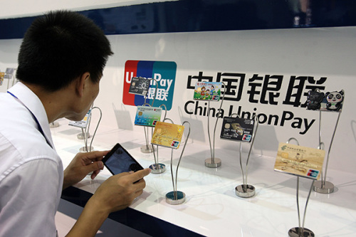 A visitor examines China UnionPay cards at an exhibition in Beijing. UnionPay International said its global strategy has two facets, one for developing economies and the other for mature economies. (Photo/China Daily)