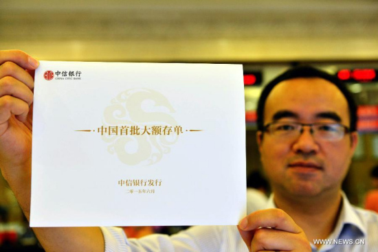 A staff member of China Citic Bank displays a certificate of deposit (CD) in Hangzhou, capital of east China's Zhejiang Province, June 15, 2015. (Photo: Xinhua/Long Wei) 