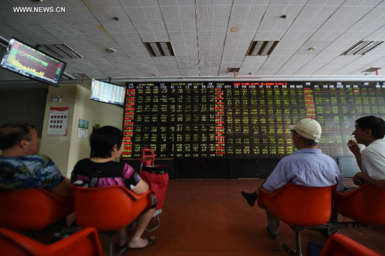 Investors look through stock information at a trading hall in a securities firm in Shenyang, capital of northeast China's Liaoning Province, June 26, 2015. (Photo: Xinhua/Pan Yulong)