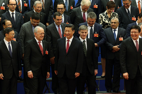 President Xi Jinping joins with envoys of governments that signed onto the Chinese-led Asian Infrastructure Investment Bank at the Great Hall of the People in Beijing on Monday. (Photo/China Daily)